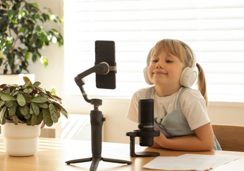 Young girl with headphones smiling during a solo podcast session, equipped with mic